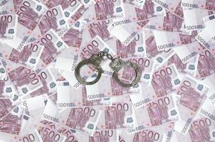 Handcuffs on five hundred euros background. Financial crime, dirty money and corruption concept - 500 money bills and dirty steel handcuffs photo