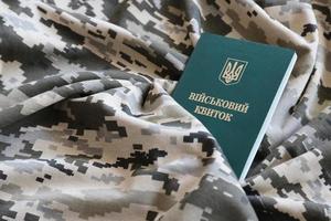 Ukrainian military ID on fabric with texture of pixeled camouflage. Cloth with camo pattern in grey, brown and green pixel shapes with Ukrainian army personal token photo