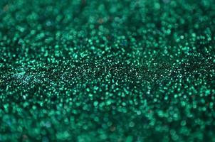 A huge amount of green decorative sequins. Background texture with shiny, small elements that reflect light in a random order. Glitter texture photo