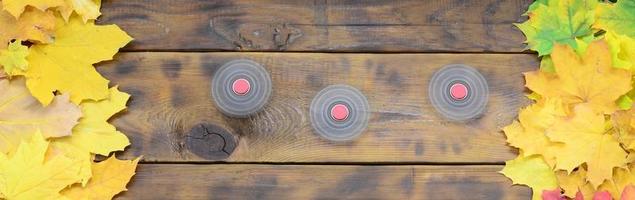 Several spinners among the many yellowing fallen autumn leaves on the background surface of natural wooden boards of dark brown color photo