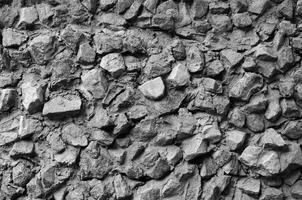 The texture of a strong stone wall of many concreted stones of various shapes photo