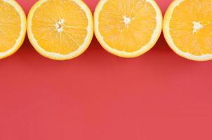 Top view of a several orange fruit slices on bright background in red color. A saturated citrus texture image photo