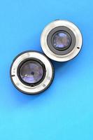 Two photographic lenses lie on a bright blue background. Space for text photo