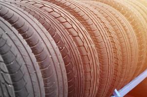 Rack with variety of car tires in automobile store. Many black tires. Tire stack background. Selective focus photo