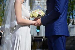 The newlywed couple is holding a beautiful wedding bouquet. Classical wedding photography, symbolizing unity, love and the creation of a new family photo