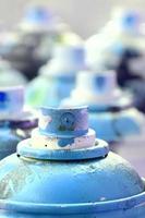 A lot of dirty and used aerosol cans of bright blue paint. Macro photograph with shallow depth of field. Selective focus on the spray nozzle photo