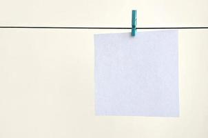 White blank cards on rope, light wall background. Creative reminder, small sheets of paper on old clothespin, memo backdrop photo