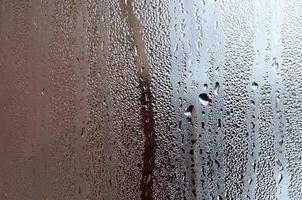 Texture of a drop of rain on a glass wet transparent background. Toned in grey color photo