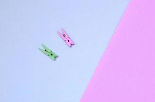 Two colored wooden pegs lie on texture background of fashion pastel violet and pink colors paper photo