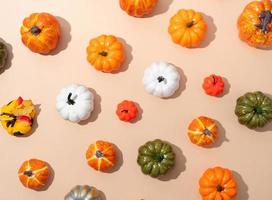 pattern of colorful artificial pumpkins on orange background photo