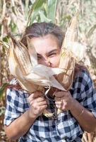 portrait of funny female woman in corn crop holding cobs making funny faces photo