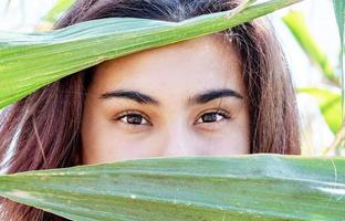 closeup shot of caucasian woman covering face with corn leaves photo