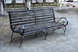 Wooden bench in a summer park in the city. Bench close-up in the afternoon. photo