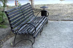 Wooden bench in a summer park in the city. Bench close-up in the afternoon. photo