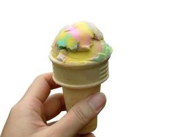 recorte cerrar una mano sosteniendo helado de color arco iris en cono de gofre, transparente, aislado con trazado de recorte foto