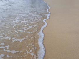 salpicaduras de olas blancas en la playa de arena para papel tapiz de fondo natural, espacio de copia foto