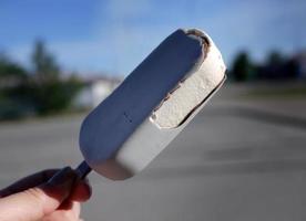 una mano sosteniendo helado de paleta con sabor a champán en la mano, en verano, cielo azul de fondo borroso, espacio de copia foto