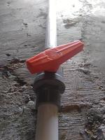 válvula de agua con manija roja conectada a tubería de pvc foto