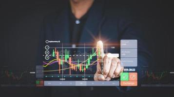 Businessman or trader is pointing a growing virtual hologram stock, planning analyze indicator and strategy buy and sell, Stock market, Business growth, progress or success concept.nvest in trading photo