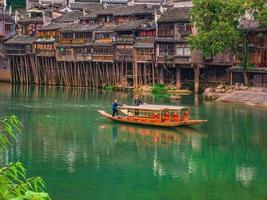 fenghuang,Hunan.China-16 October 2018.Unacquainted tourist sightseeing fenghuang old town architecture by boat in the river.phoenix ancient town or Fenghuang County is county of Hunan Province, China photo