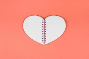 Blank heart shaped notepad on coral background photo