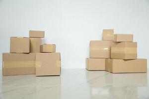 Stack of cardboard boxes for moving, Empty room with a white wall and cardboard boxes with unbranded barcode on the floor. Delivery of goods, shopping. Cardboard boxes on gray wall background. photo