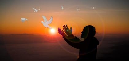 Concept of worship in Christianity. Doves fly into man hands. Christians have faith in Holy Spirit. Male silhouette worship to god with love Faith,Spirit and jesus christ. Christian praying for peace photo