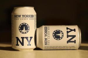 TERNOPIL, UKRAINE - JULY 18, 2022 Two cans of New Yorker fine lager beer with original logo and design on brown retro background photo