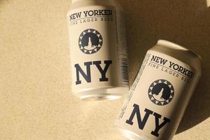 TERNOPIL, UKRAINE - JULY 18, 2022 Two cans of New Yorker fine lager beer with original logo and design on brown retro background photo