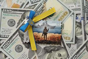 ternopil, ucrania - 2 de septiembre de 2022, famoso matasellos ucraniano con un buque de guerra ruso y un soldado ucraniano como recuerdo de madera en una gran cantidad de billetes de dólares estadounidenses foto