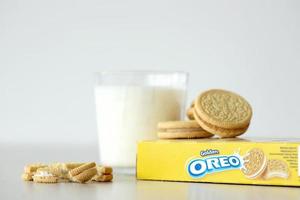 TERNOPIL, UKRAINE - MAY 28, 2022 Oreo golden crispy cookies with glass of milk on white background. The brand Oreo is owned by company Mondelez international photo