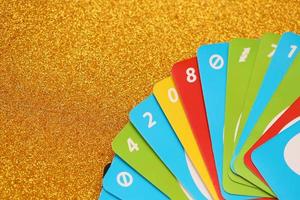 TERNOPIL, UKRAINE - MAY 15, 2022 Many colorful UNO game cards on golden background. UNO is an American shedding-type card game that is played with a specially printed deck photo