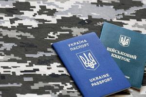 Ukrainian military ID and foreign passport on fabric with texture of pixeled camouflage. Cloth with camo pattern in grey, brown and green shapes with Ukrainian army personal token and passport. photo