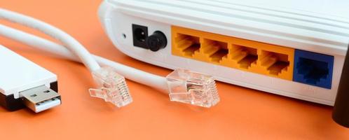 Internet router, portable USB wi-fi adapter and internet cable plugs lie on a bright orange background. Items required for internet connection photo