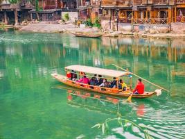 fenghuang,Hunan.China-16 October 2018.Unacquainted tourist sightseeing fenghuang old town architecture by boat in the river.phoenix ancient town or Fenghuang County is county of Hunan Province, China photo