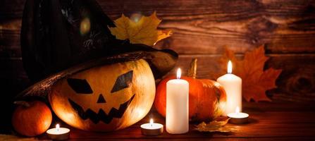 Pumpkin lantern and holiday candles on wooden background. Halloween symbol. photo