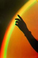 Shadow of womans hand. Rainbow reflection of sunbeam on wall. Hand touches rainbow. photo
