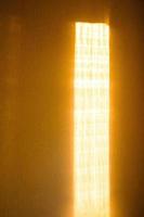 Sunbeam on yellow wall of house. Surface texture with sun glare. photo