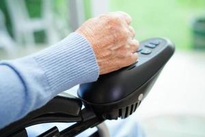 Asian elderly woman disability patient sitting on electric wheelchair in park, medical concept. photo