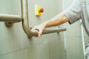 Asian elderly old woman patient use toilet support rail in bathroom, handrail safety grab bar, security in nursing hospital. photo