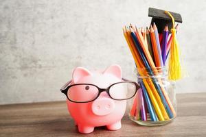 Pigging bank wearing eyeglass with coins and calculator saving bank education concept. photo