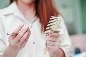 Asian woman have problem with long hair loss attach to comb brush. photo