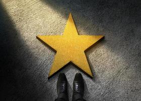 éxito en el concepto de talento empresarial o personal. vista superior del hombre de negocios con zapatos oxford brillantes parados frente a una estrella dorada en el piso de cemento oscuro foto