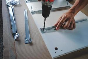 Assembling Furniture at Home. Moving for a New House or DIY Concept. Craftsman using Cordless Screwdriver to Installing the Cabinet to Installing the Cabinet. photo