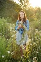 Beautiful girl  walking on field on summer with wildflowers. photo