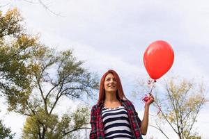Below view of happy woman with red balloon in the park. photo