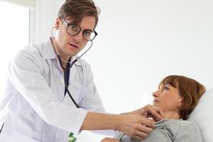 the doctor is examining the patient in the hospital. white male doctor examining an elderly female white patient. photo