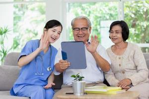 Nursing Home Care concept. Beautiful Asian nurse and elderly person using tablet video call online Chatting with family while in nursing home. photo