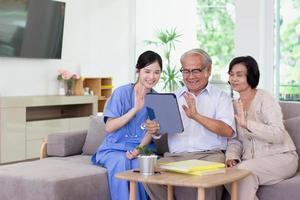 Nursing Home Care concept. Beautiful Asian nurse and elderly person using tablet video call online Chatting with family while in nursing home. photo
