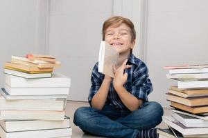 Happy schoolboy among heap of books. photo